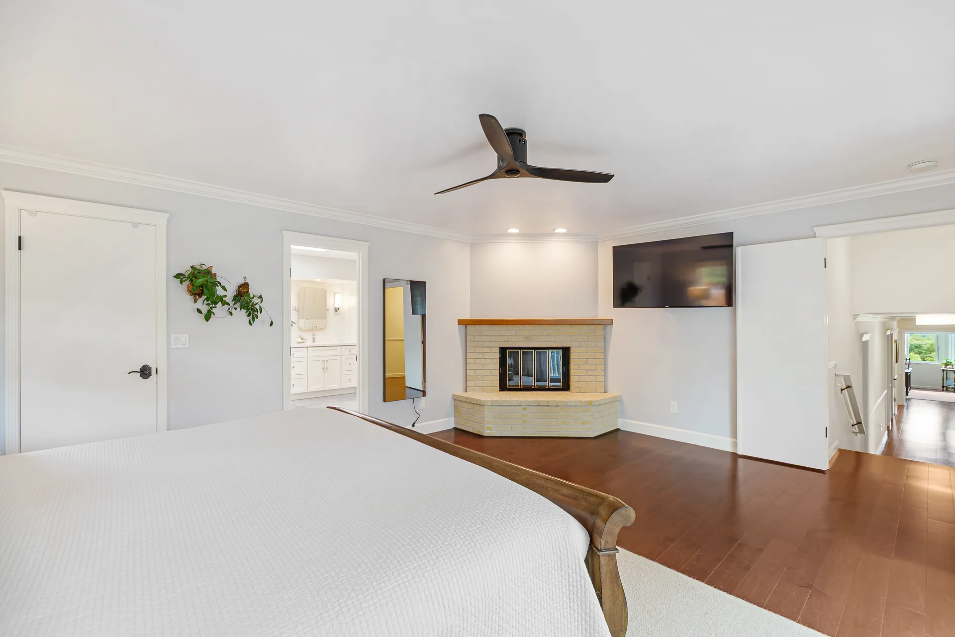 Primary bedroom with corner fireplace, engineered hardwood flooring, and daylight