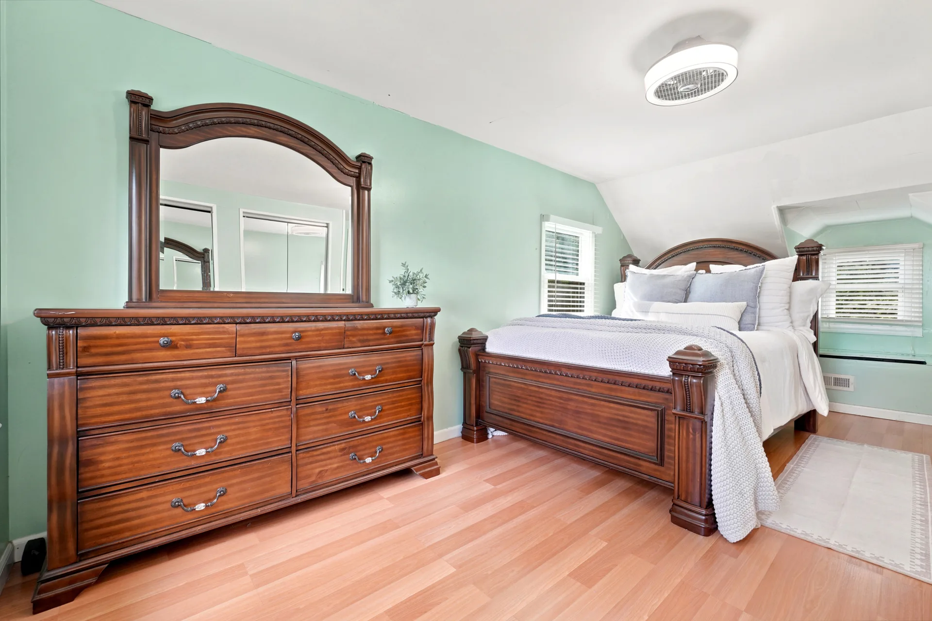 Primary bedroom upstairs with mint green walls and light wood flooring