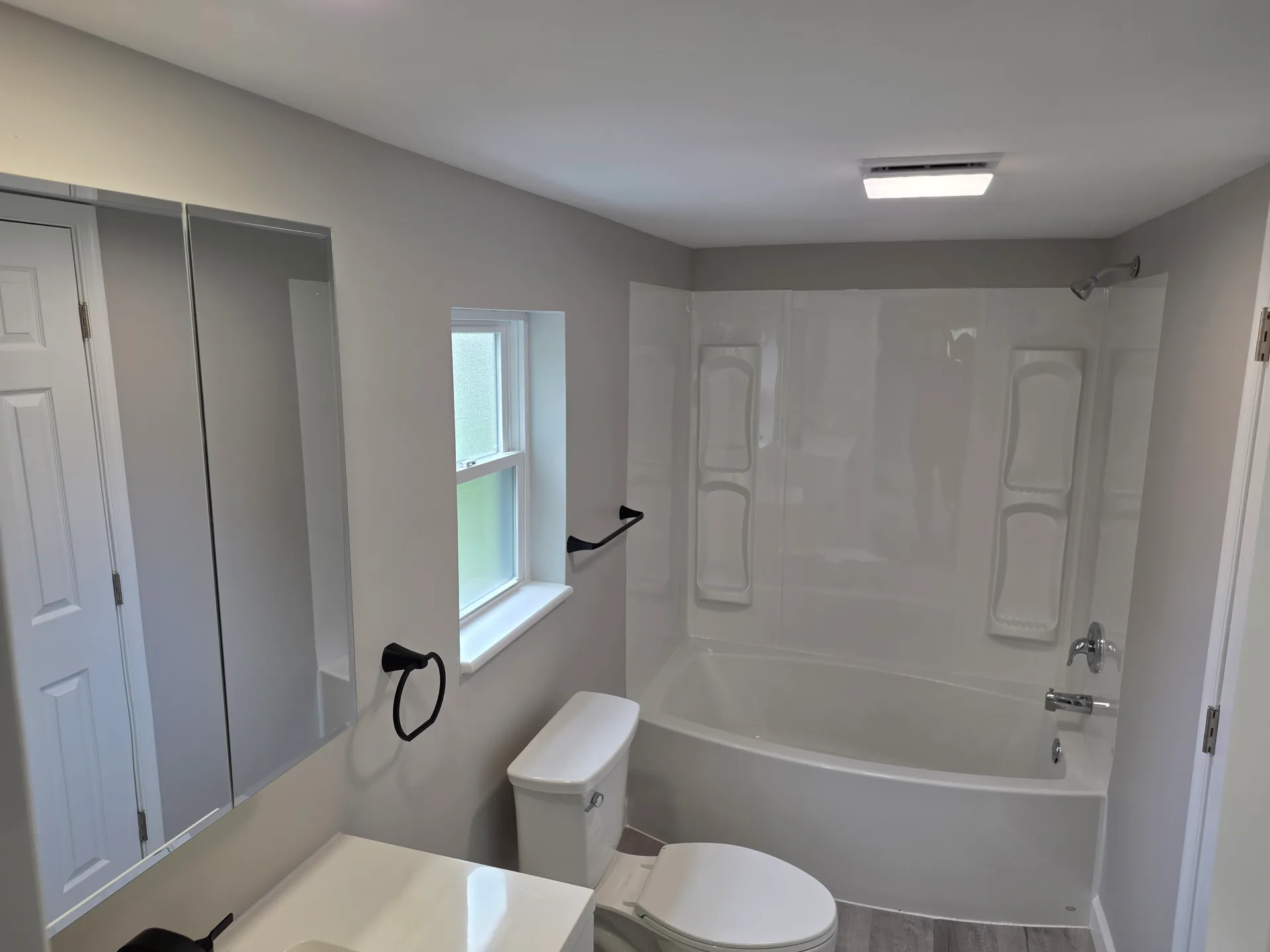 Renovated full bathroom with white vanity and tub-shower surround
