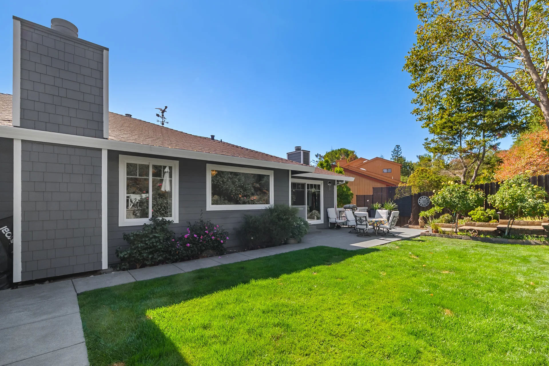 Backyard with grassy lawn and custom paver patio against the rear of the home