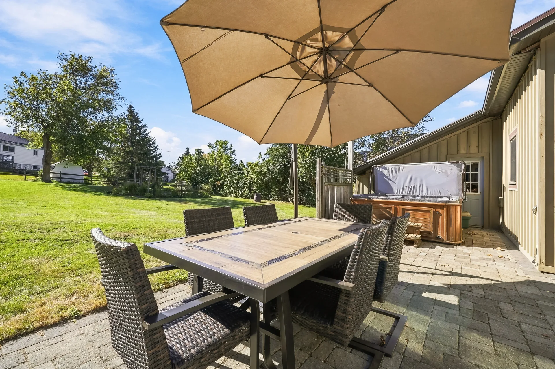 Backyard patio dining area with covered hot tub beyond
