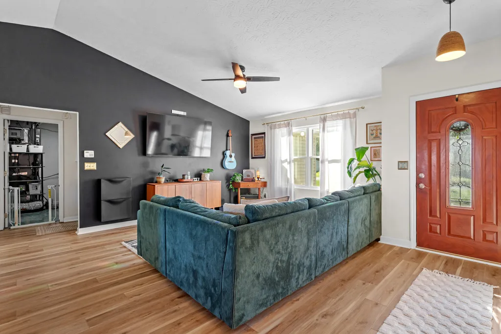 Vaulted living room with a dark accent wall and natural daylight