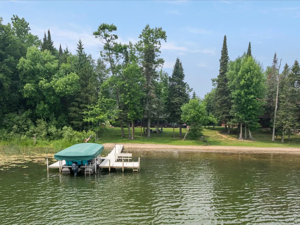 Sandy beach viewed from the water with the wooded lot behind
