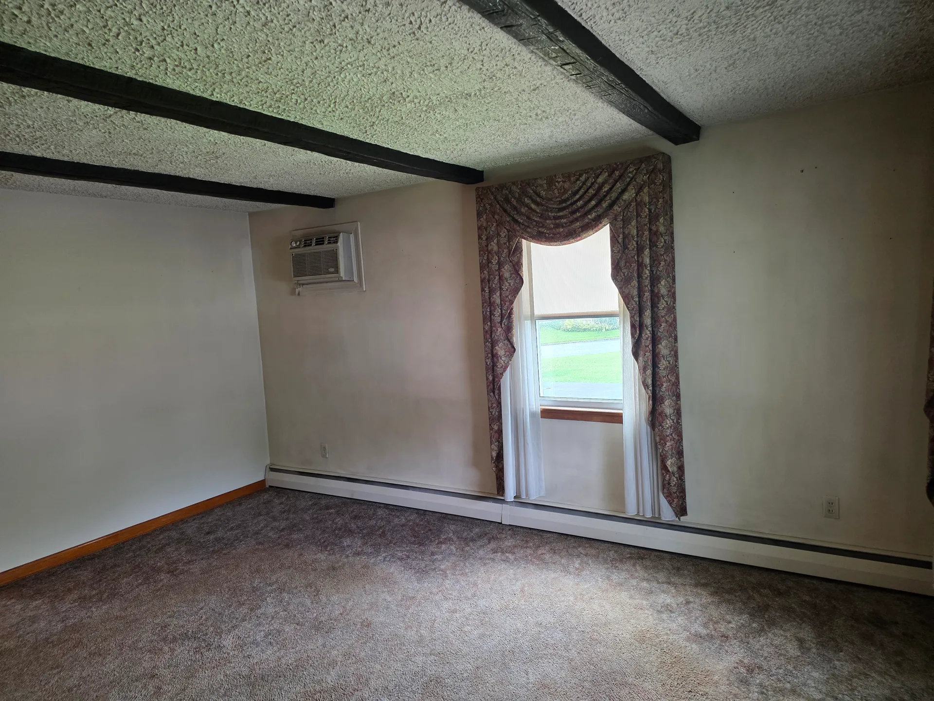 Bedroom with exposed ceiling beams and carpeted floor