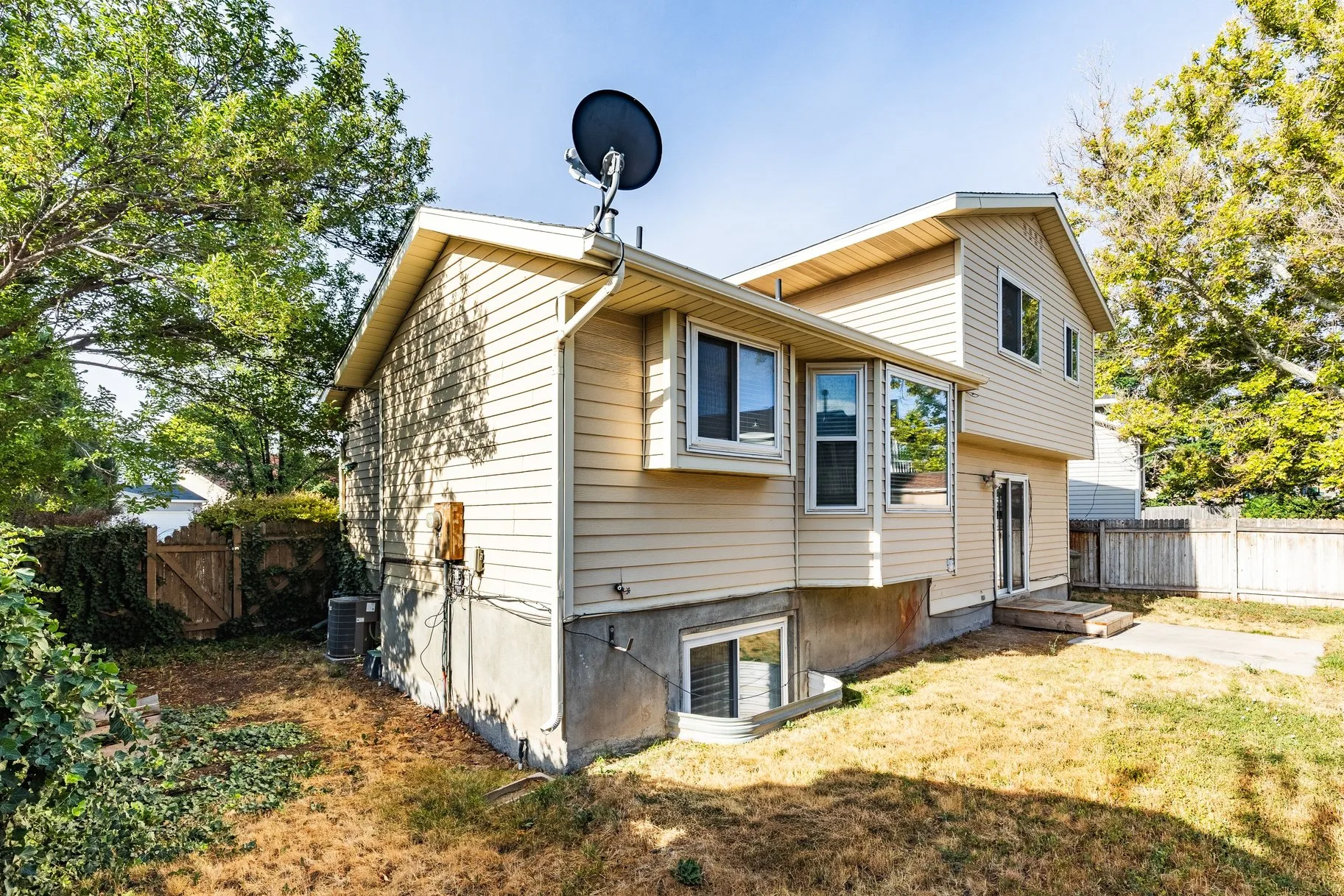 Private backyard with mature trees, fencing, and a patio area
