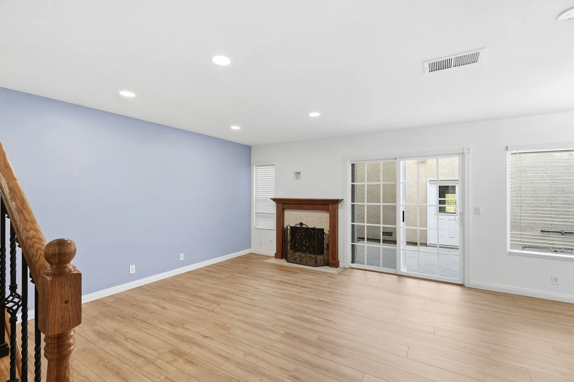 Wide view of the living room at 8 Silverwood featuring a wood-mantel fireplace and sliding glass door