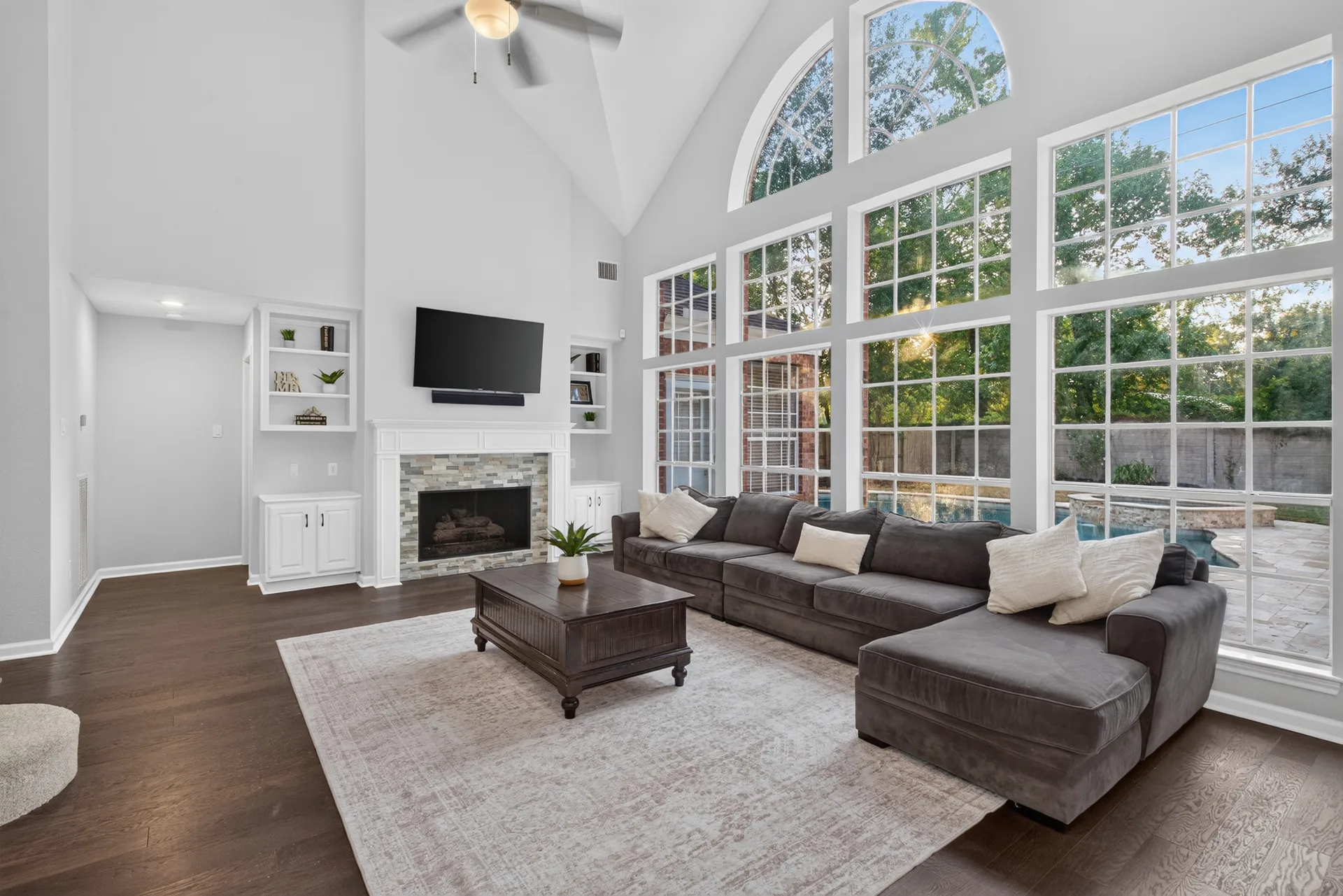 Family room with a two-story wall of windows, vaulted ceiling, and stone fireplace at 4211 Brook Shadow Dr