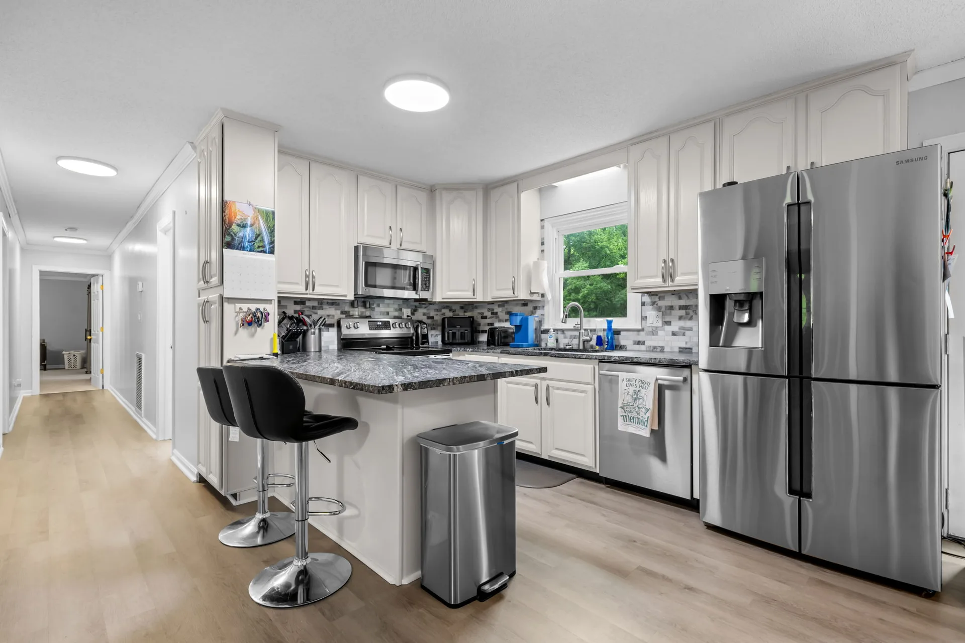 Wide view of the kitchen at 4690 Worth Pl with cream cabinetry, leathered granite counters, and a mosaic tile backsplash