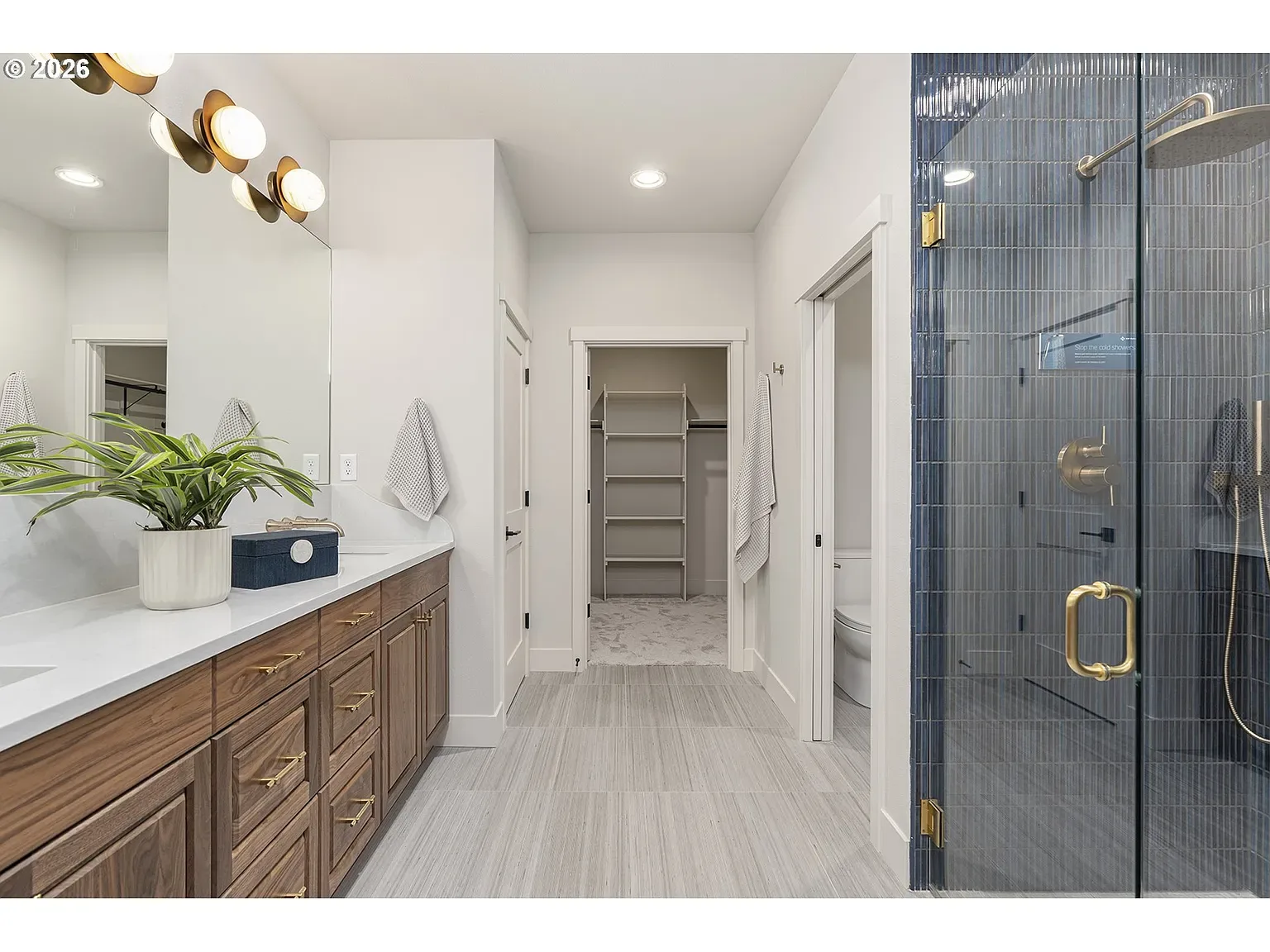 Primary bath: Walnut cabinetry, blue tile, and warm gold hardware