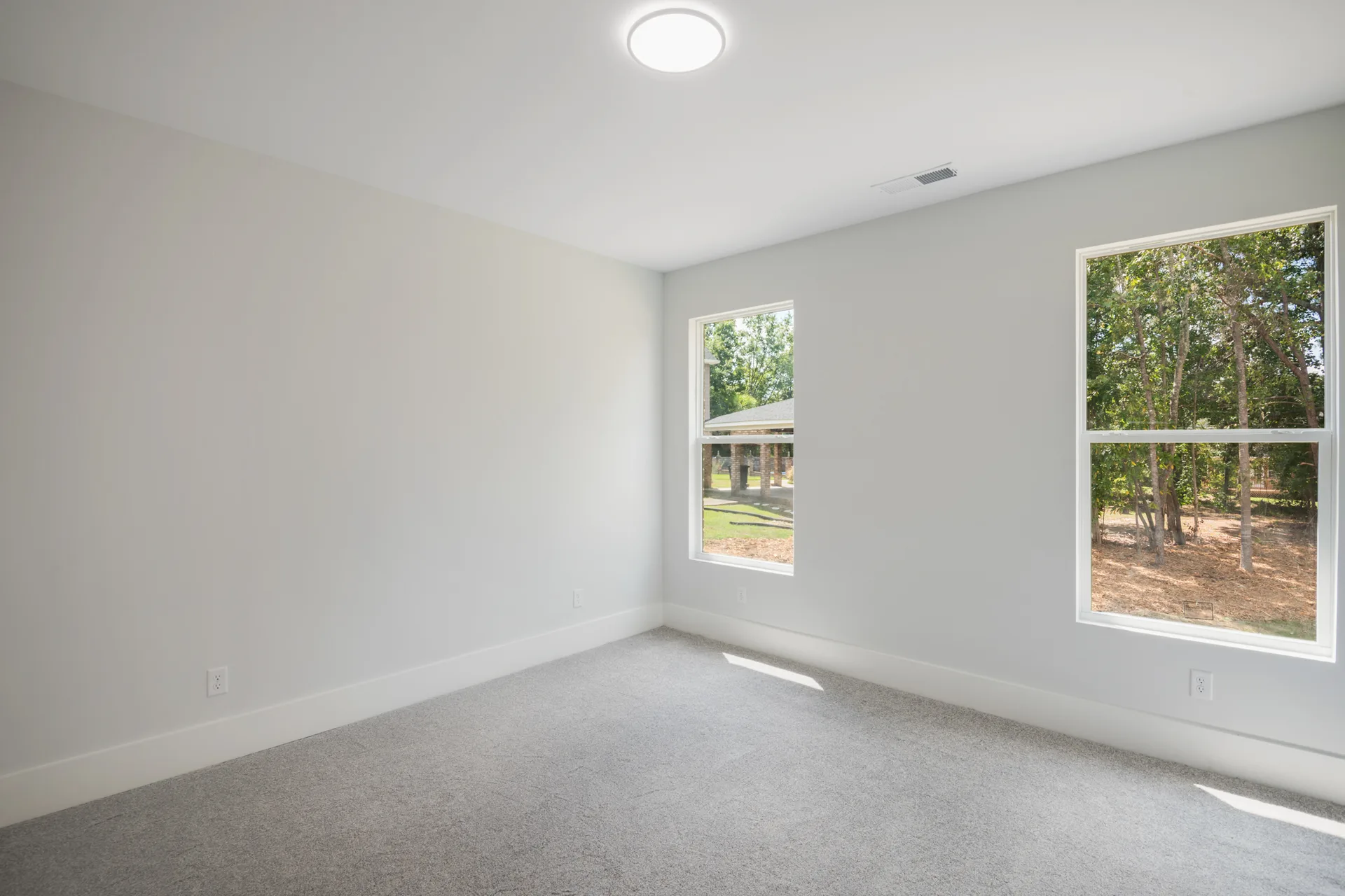 Secondary bedroom with corner windows and neutral carpet