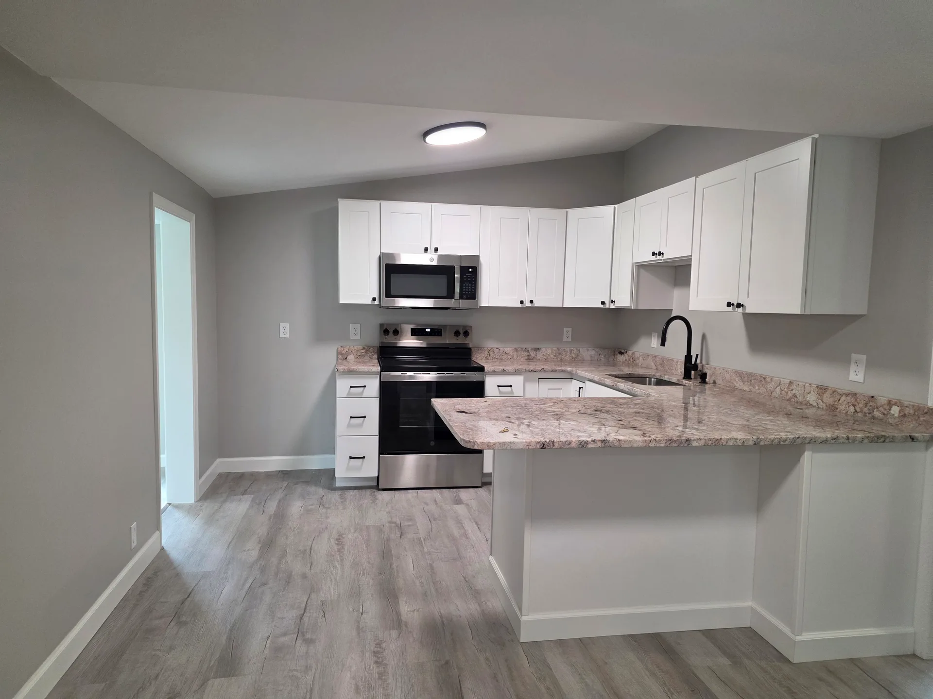 Wide view of the white eat-in kitchen with granite countertops