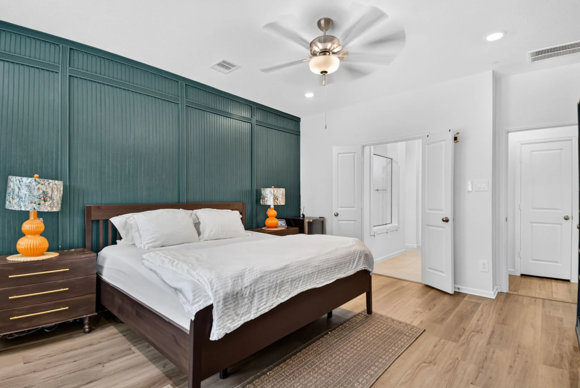 Primary bedroom featuring a dark teal beadboard accent wall in bright natural light