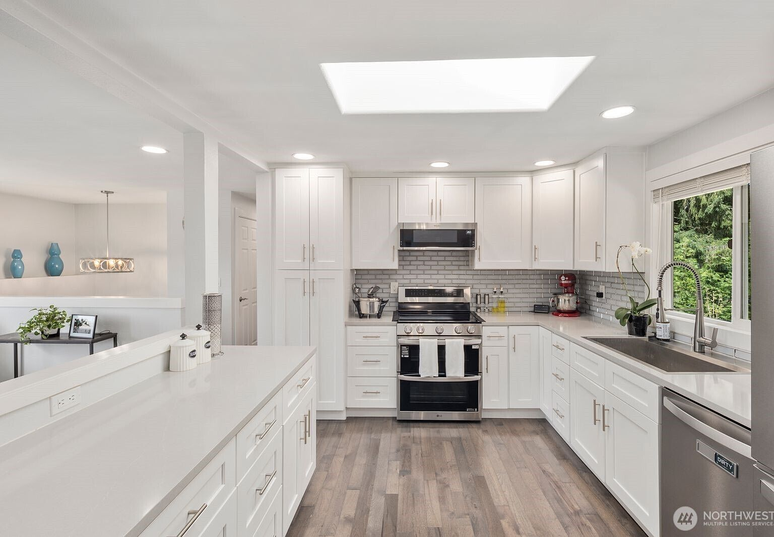 Kitchen with view into dining area, skylight overhead, and light hardwood floors