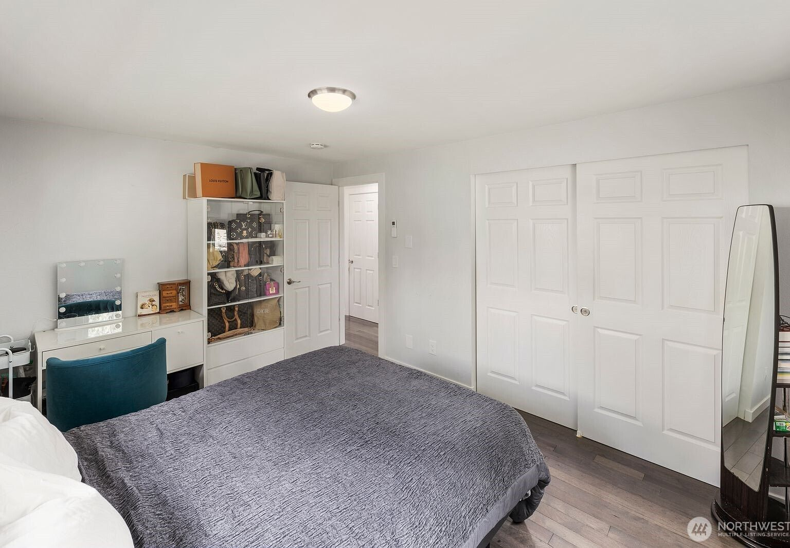 Primary bedroom with gray hardwood floors, white walls, and sliding closet doors