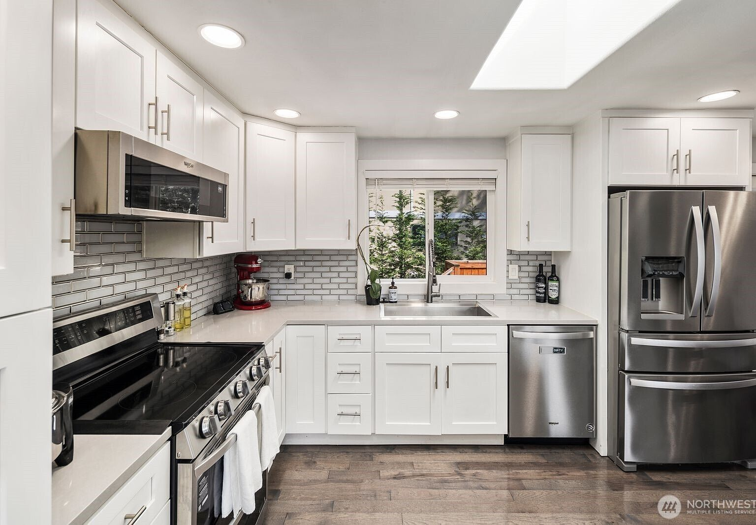 Modern kitchen with white shaker cabinets, gray brick backsplash, and quartz countertops
