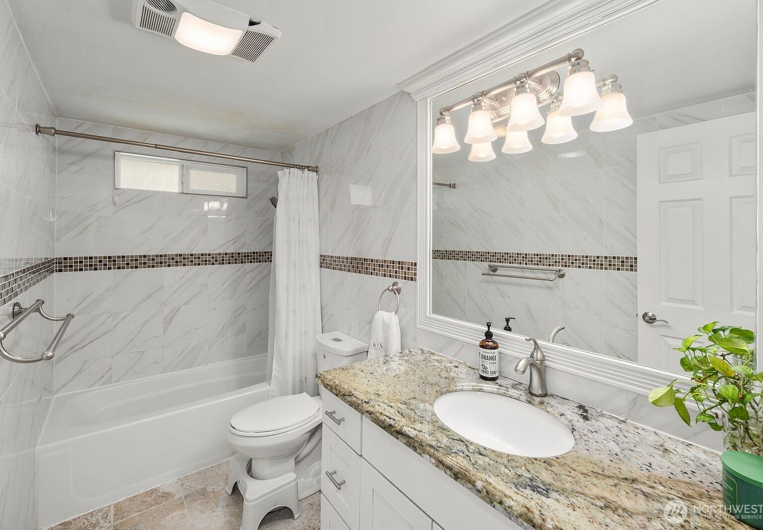 Renovated bathroom with marble-pattern tile walls, granite vanity, and bathtub-shower combo
