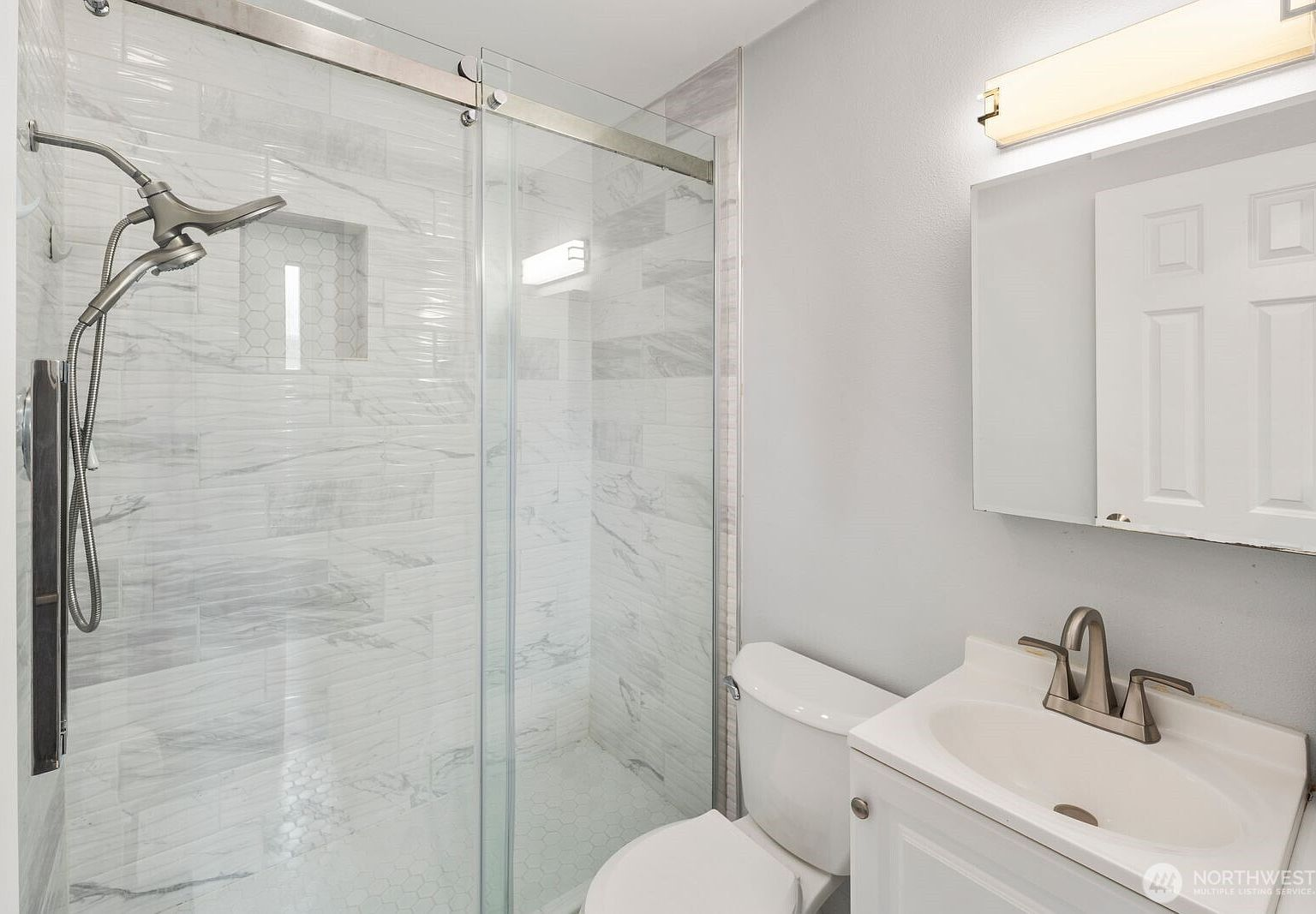 Bathroom with marble-pattern tile, brushed nickel fixtures, and bright lighting