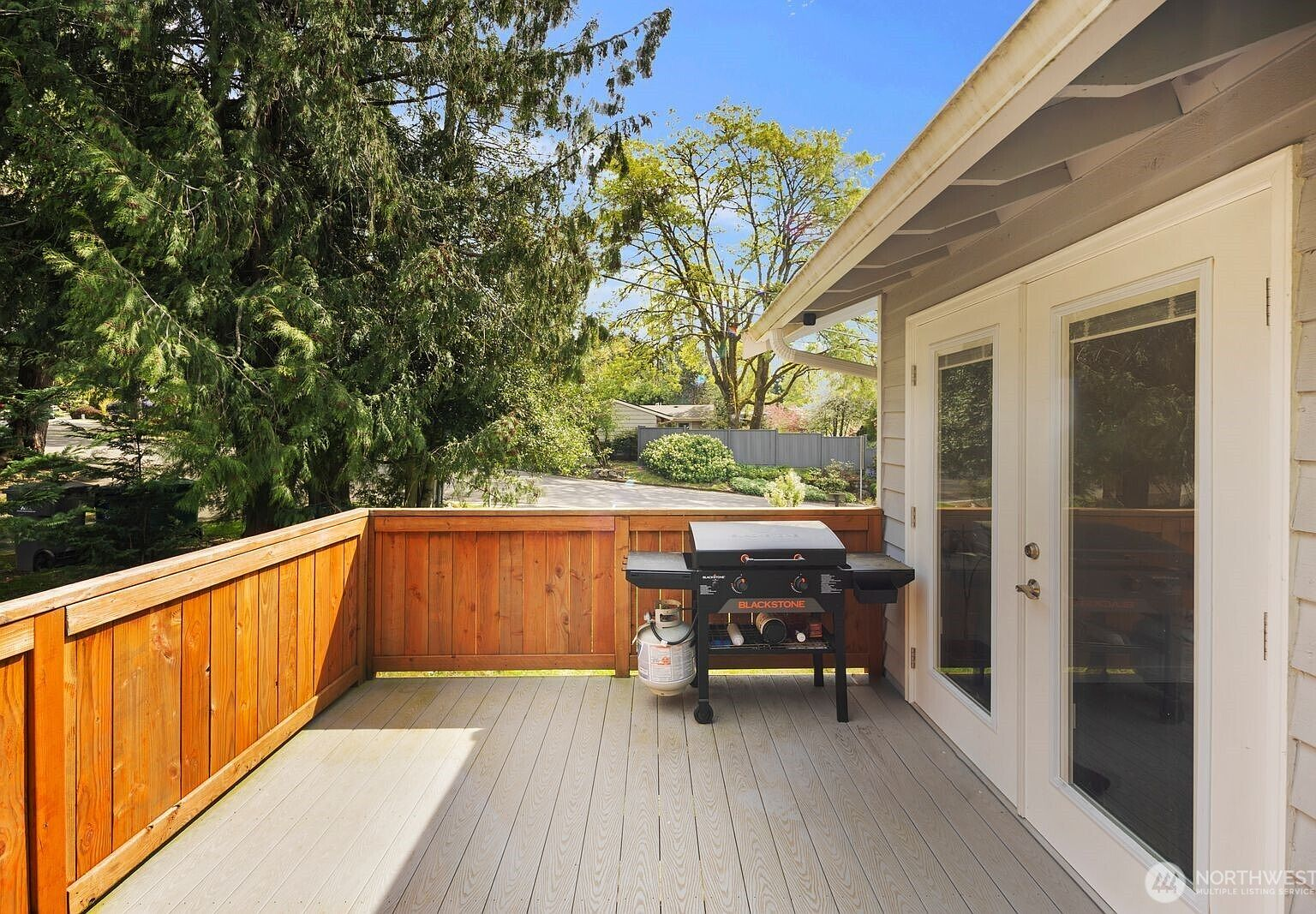 Wood deck with white French doors and view of surrounding trees