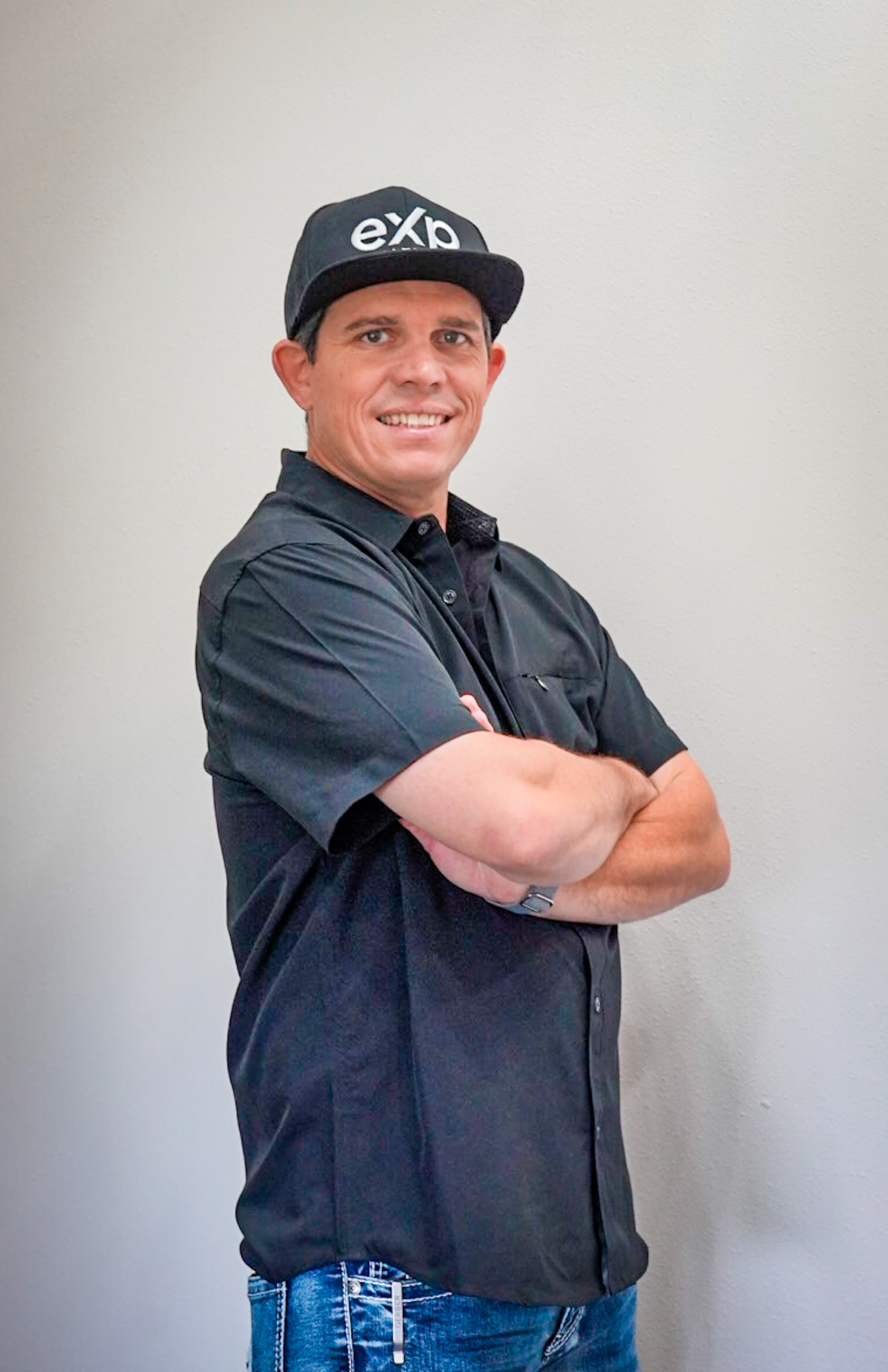 Travis Wright, REALTOR with eXp Realty, smiling with arms crossed