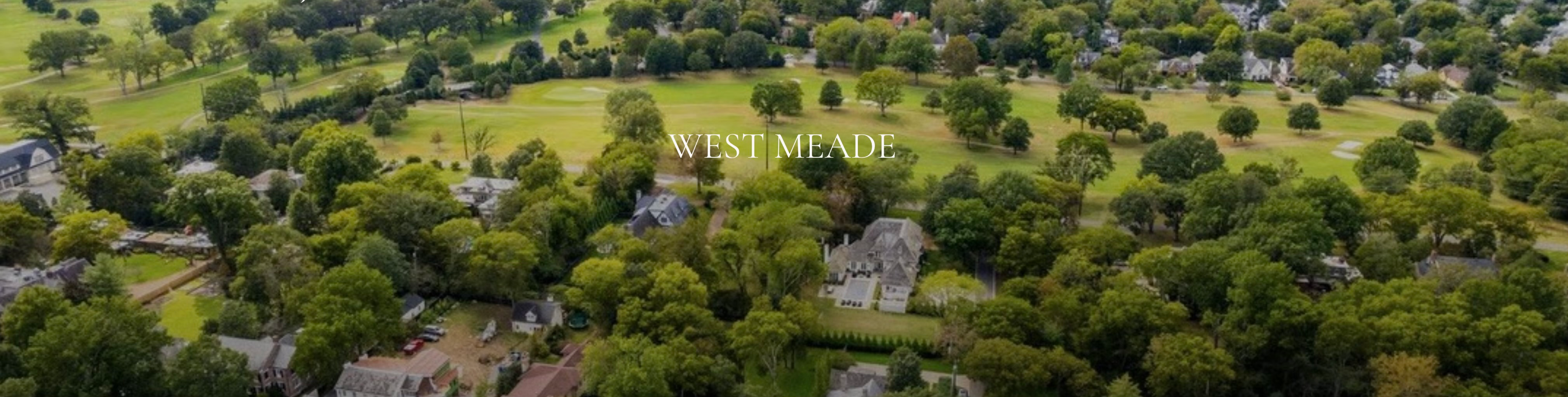 Wide aerial drone shot of the lush tree-filled neighborhood of West Meade