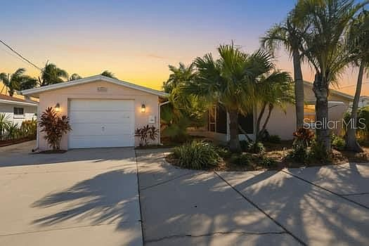 Front exterior of the home at sunset with palm trees and concrete driveway