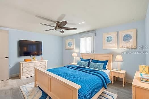 Coastal master bedroom with light blue walls and wood-look tile floors