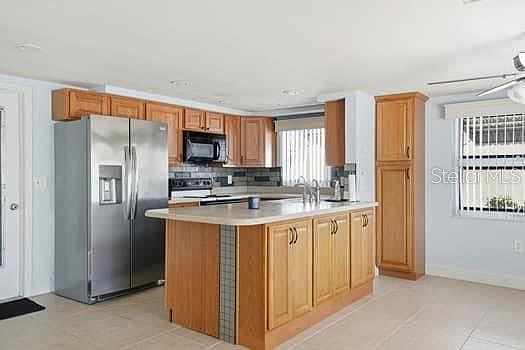 Kitchen with oak wood cabinetry, island, and stainless steel appliances