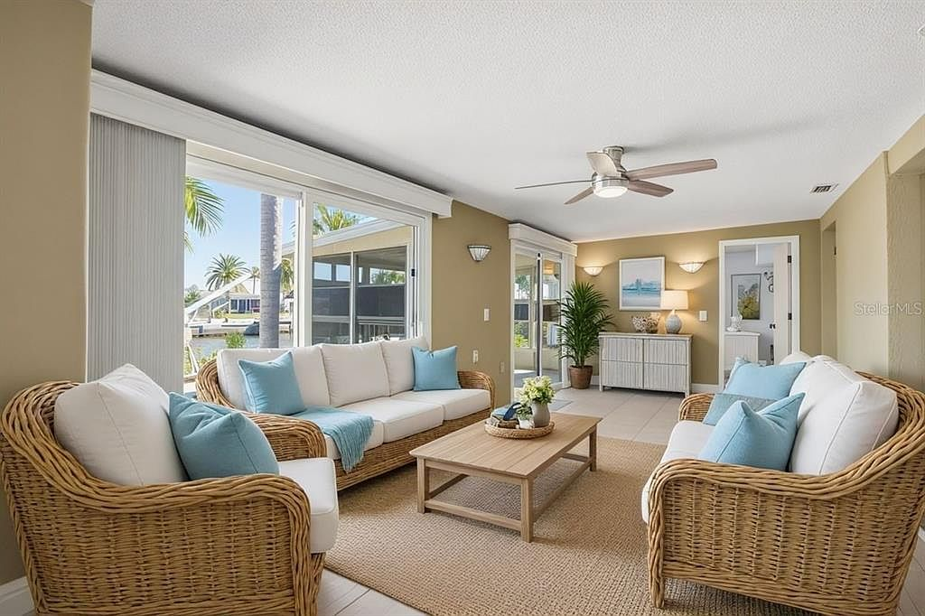 Coastal living room with wicker furniture and canal views through sliding glass doors