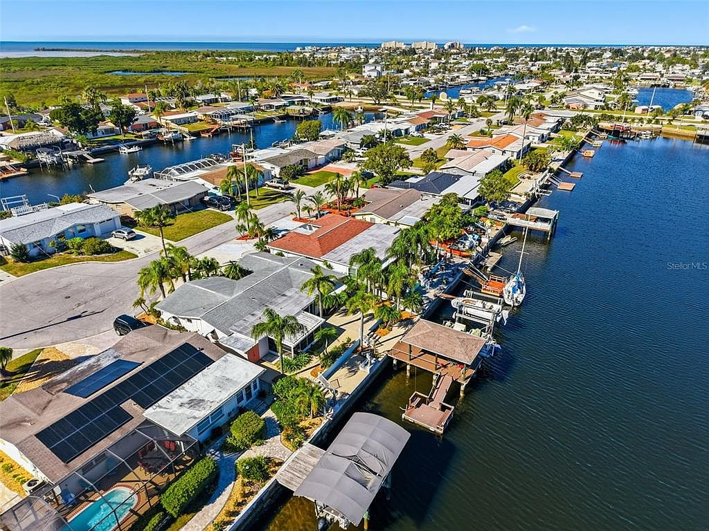 Aerial view of canal-front homes with boats and Gulf waters in the distance