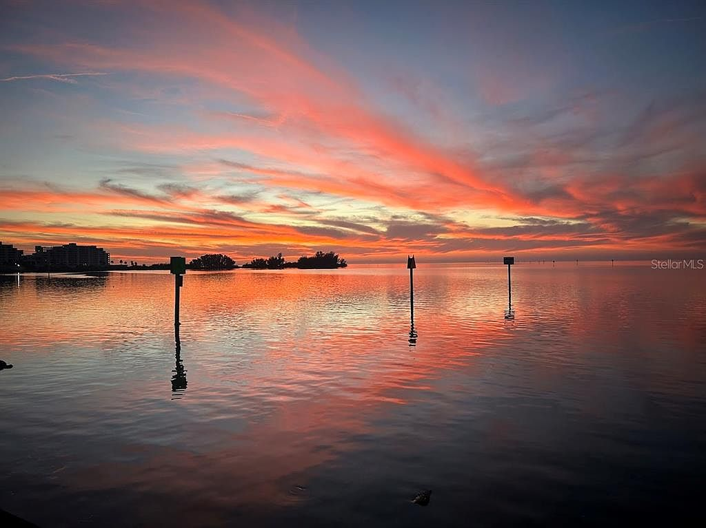 Sunset over the open Gulf waters with navigation markers silhouetted against pink and orange clouds