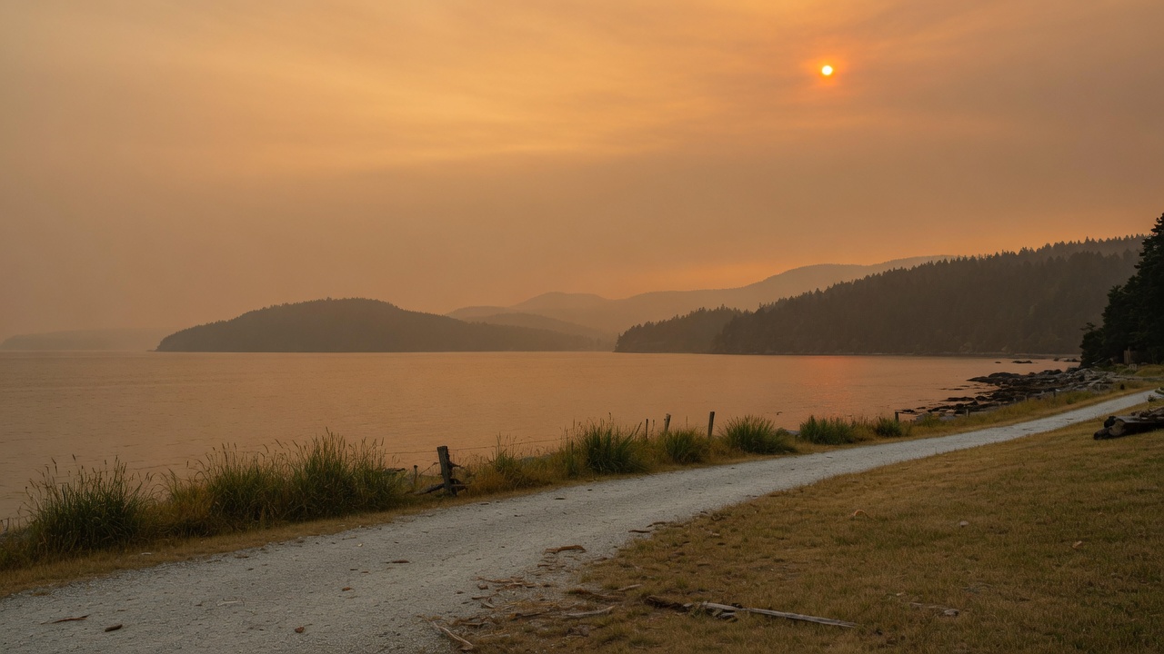 A hazy, smoke-tinged sky over a coastal British Columbia landscape during wildfire season