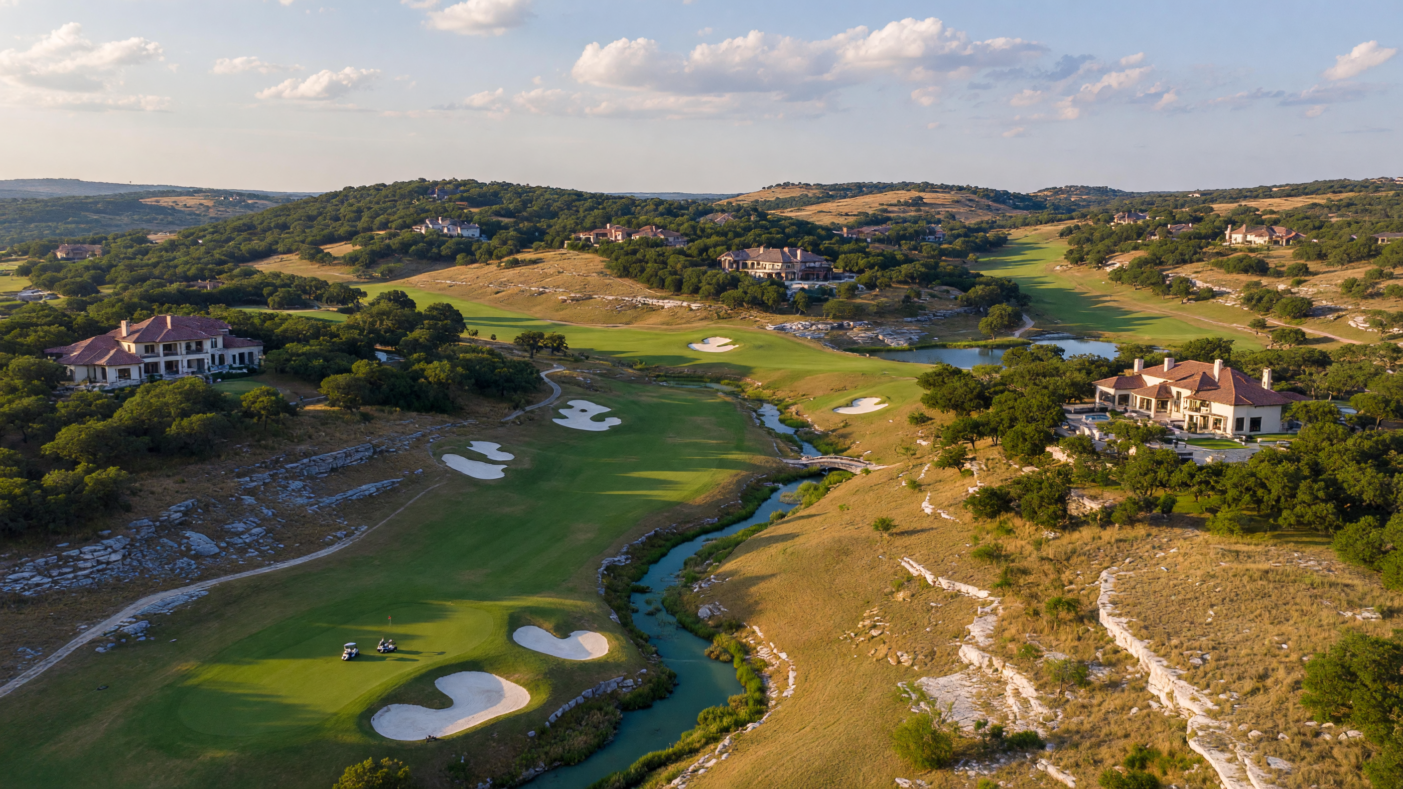 Luxury custom estate homes in a Texas Hill Country community with native limestone facades, varied architectural styles, and mature live oaks on spacious lots