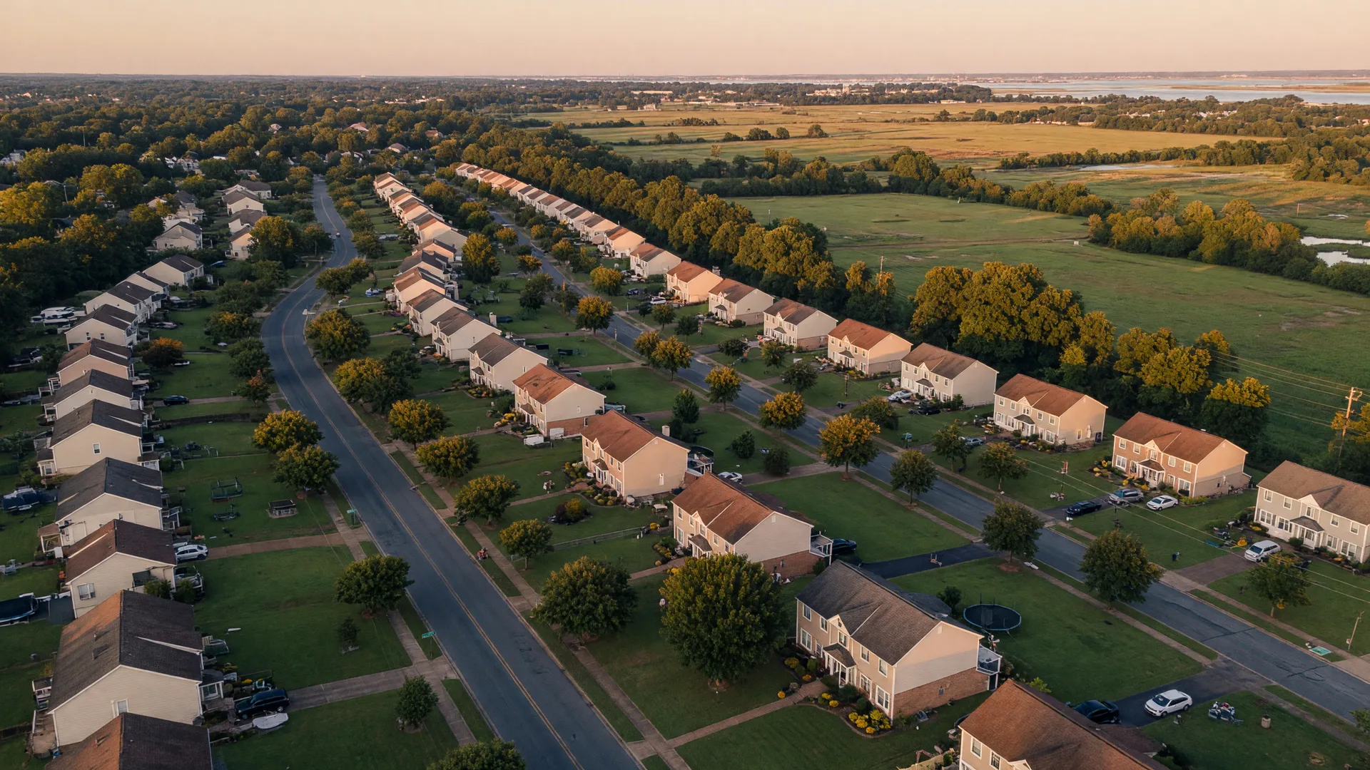 Aerial view of a Virginia suburban neighborhood with tree-lined streets and well-maintained homes at golden hour
