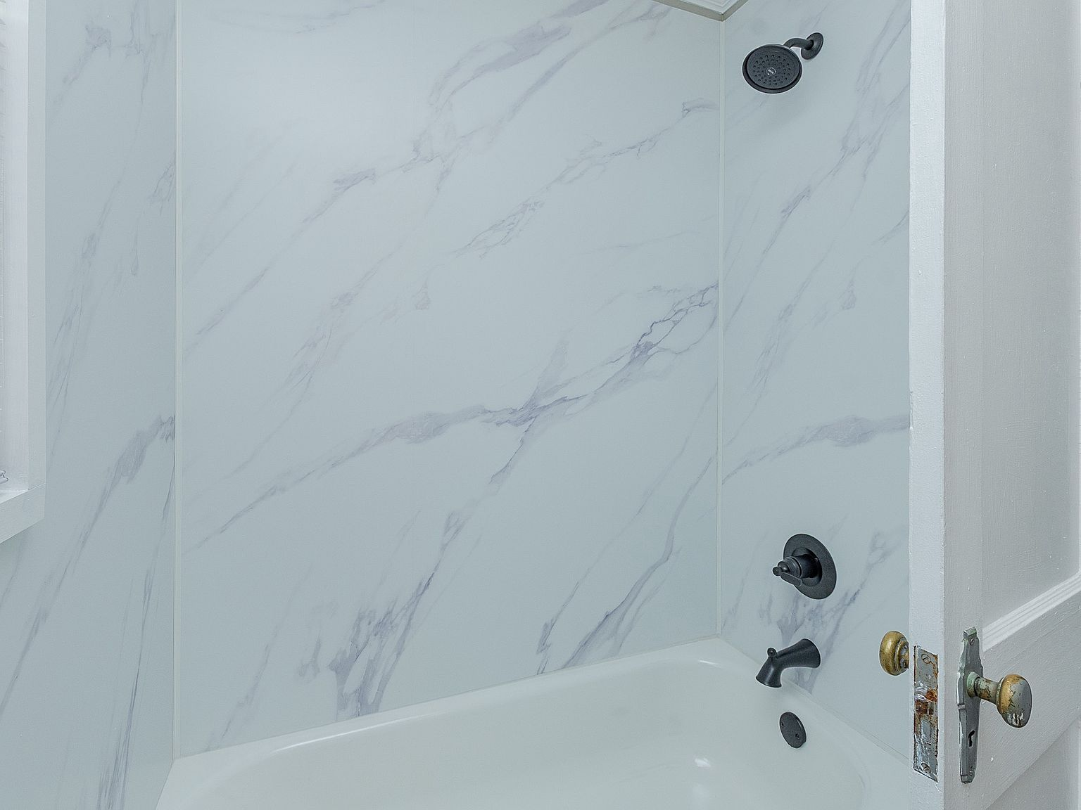 Bathroom tub and shower combo with wood floors and marble pattern tile