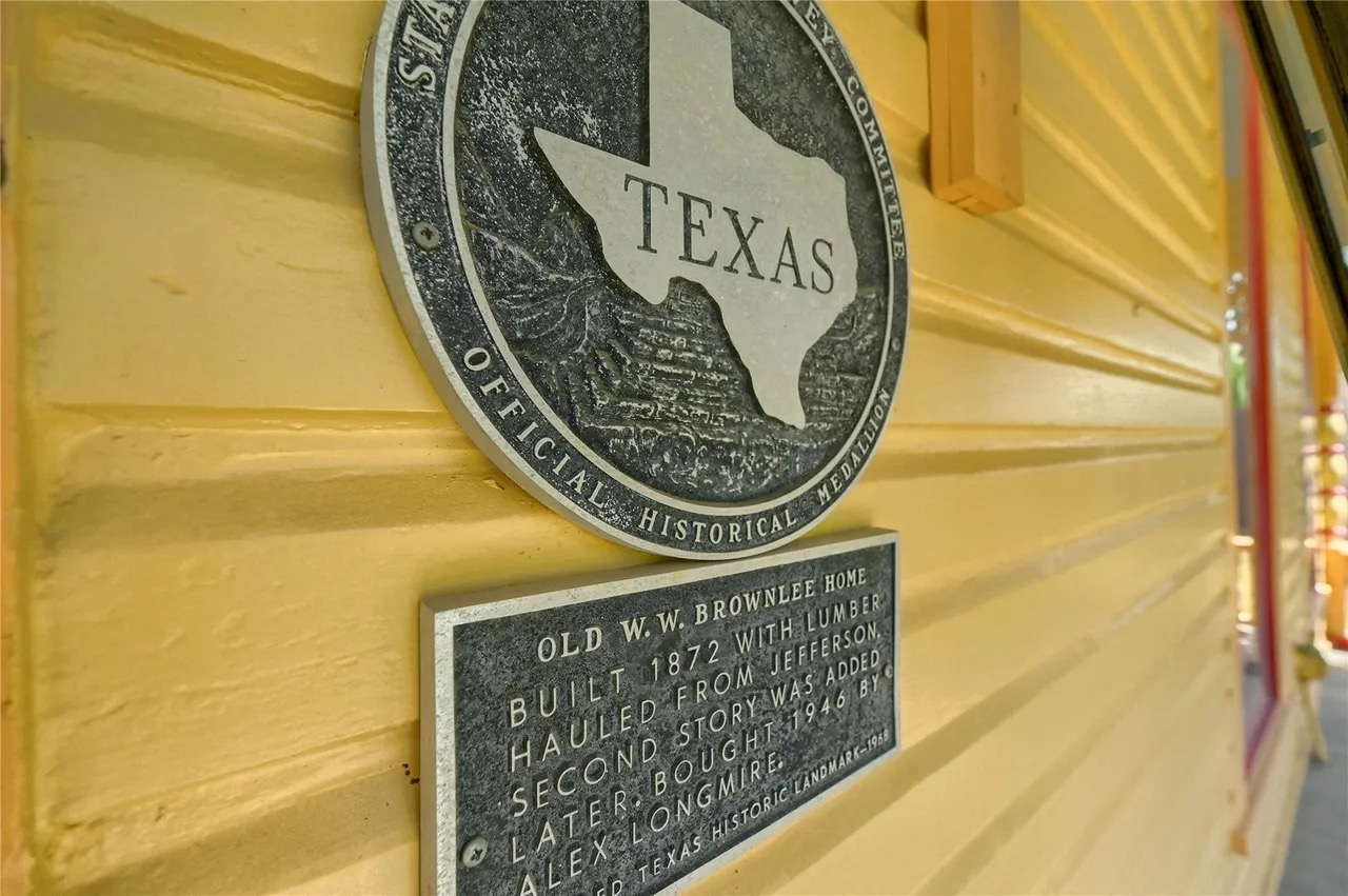 Texas Historical medallion on a yellow siding exterior wall