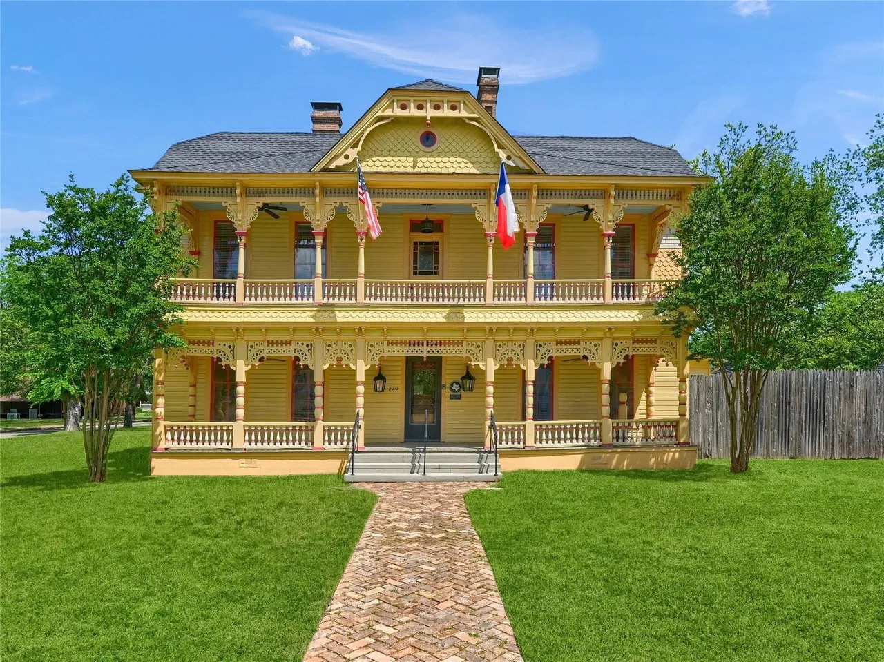 Historic yellow Victorian home in Paris TX with Texas flag