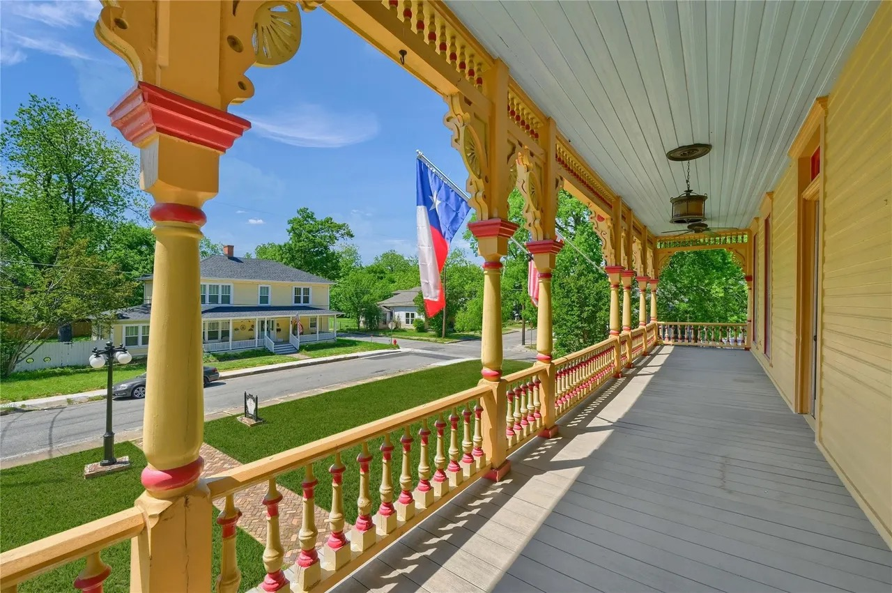 Victorian porch with ornate balustrades overlooking a neighborhood