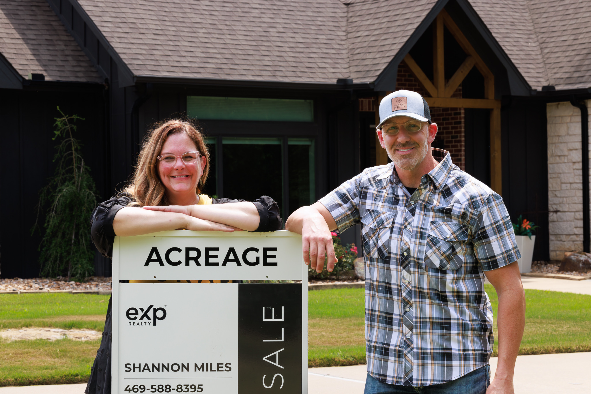 Shannon and Scott Miles leaning on an eXp Realty acreage sign