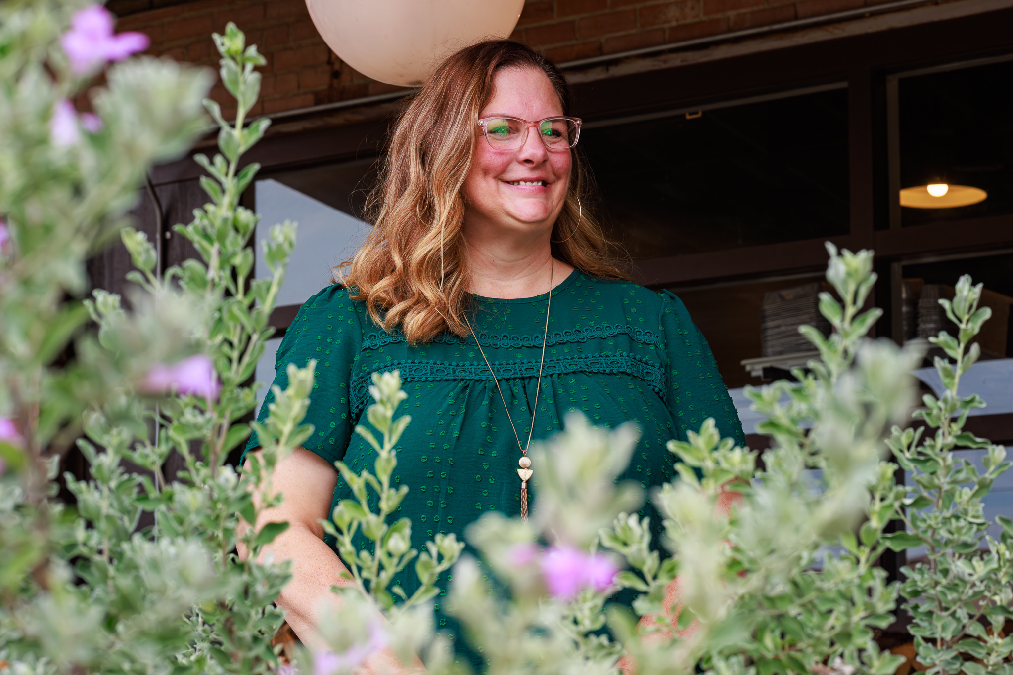 Shannon Miles portrait smiling in front of green foliage at her Paris, TX office