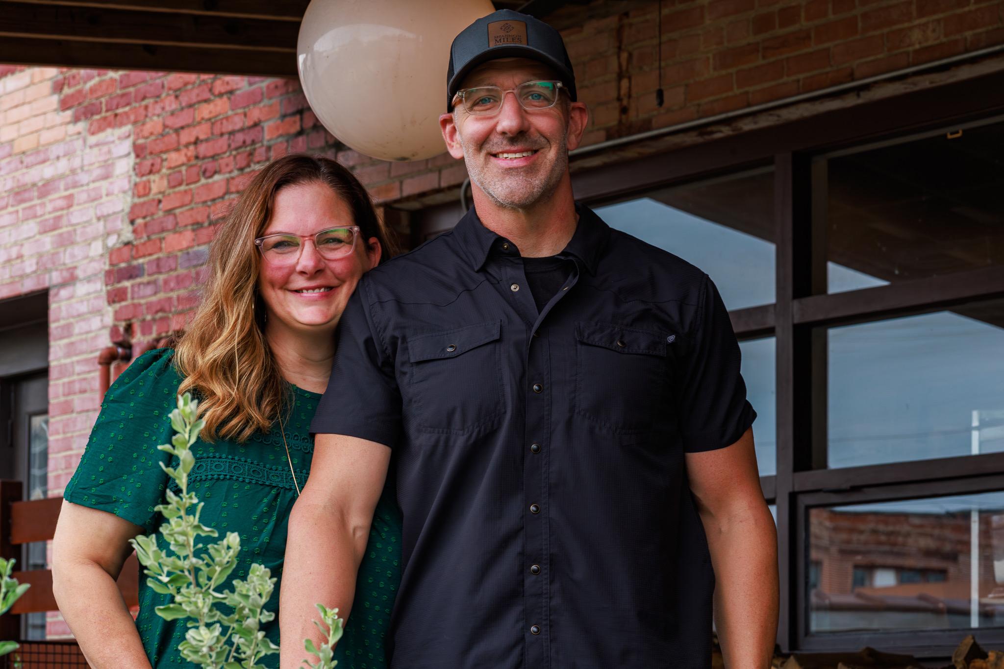 Shannon and Scott Miles, Shannon Miles Group, standing together outdoors in front of a brick building