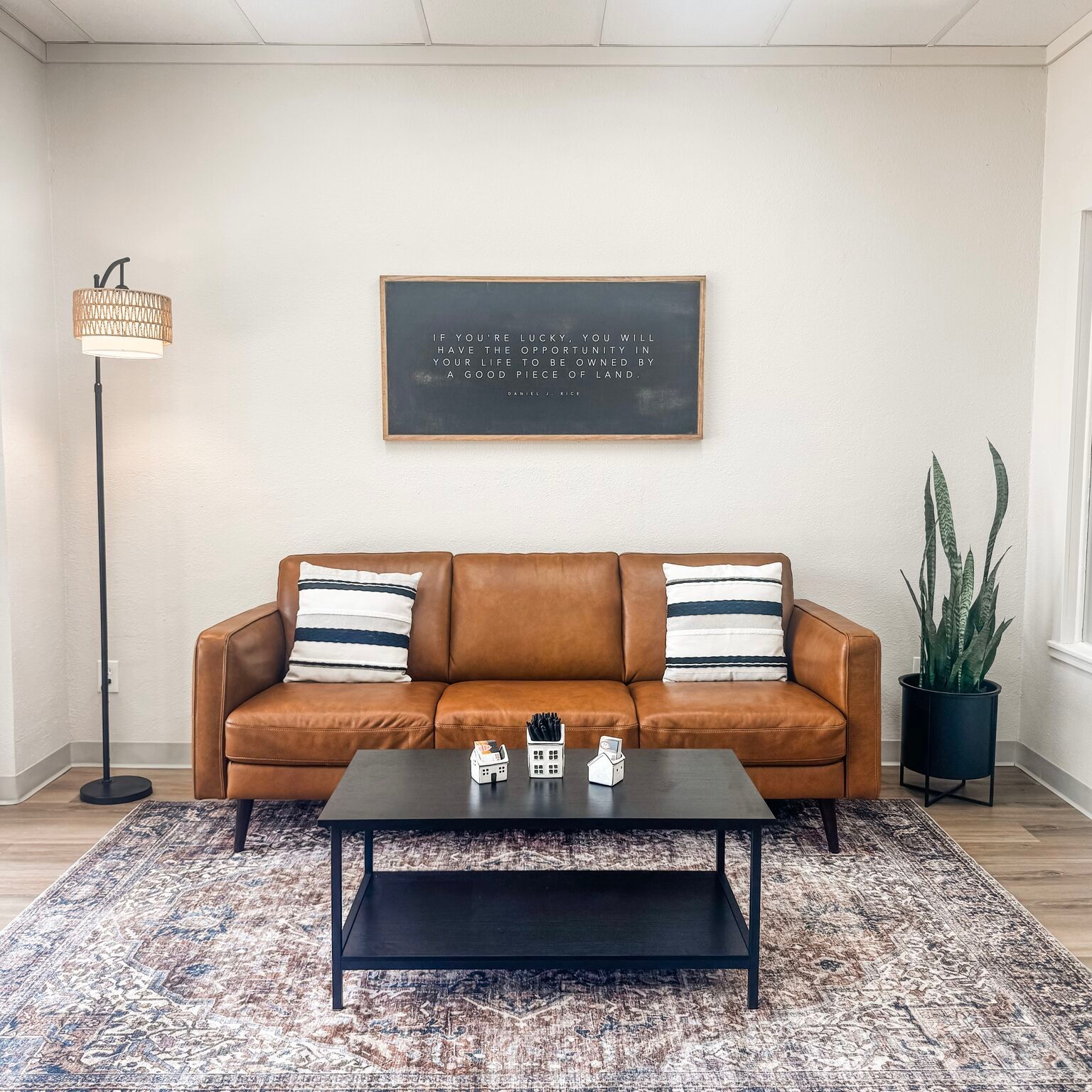 Modern office lobby of the Shannon Miles Group featuring a leather sofa and framed quote about owning land