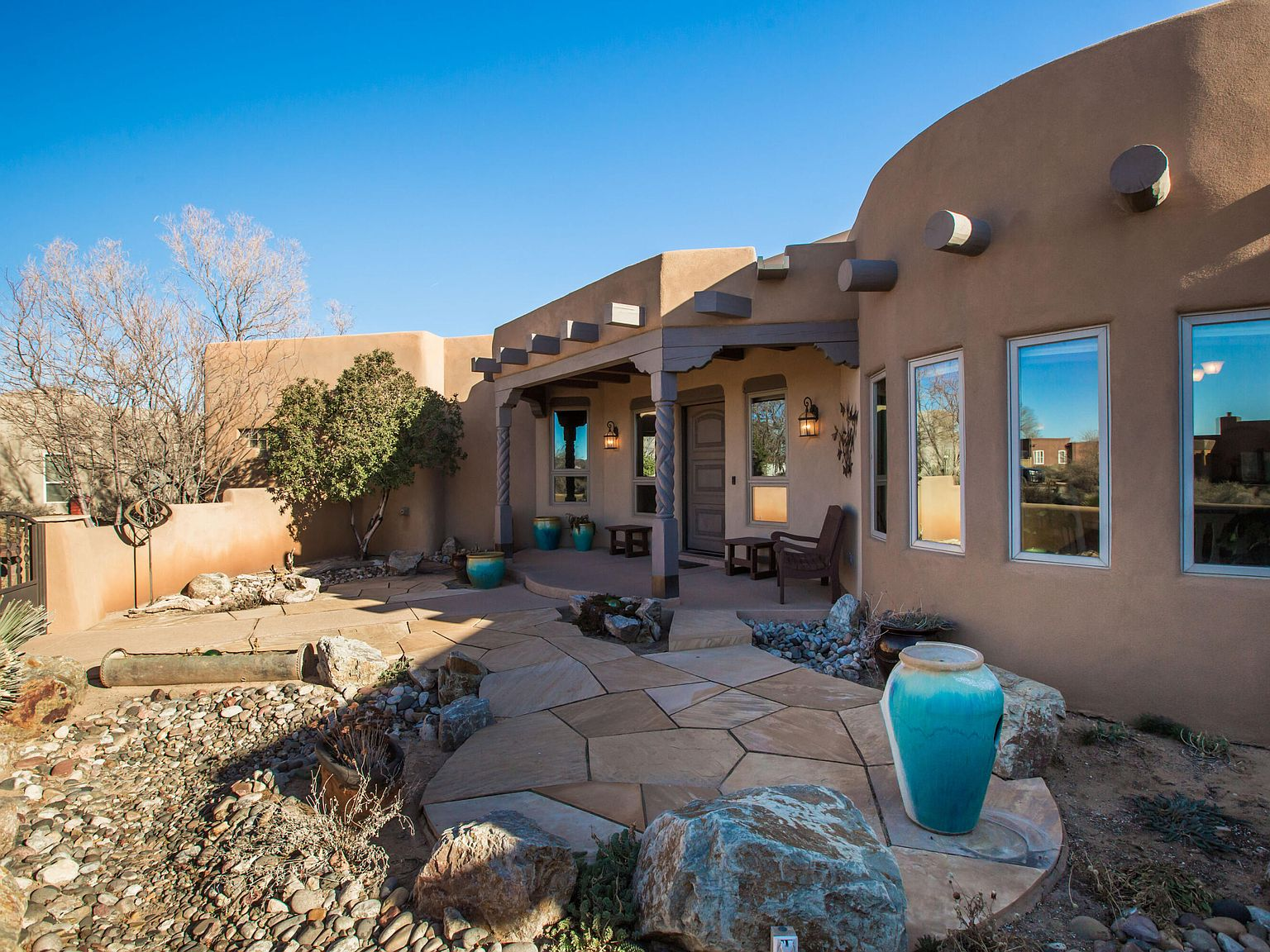 Pueblo-style courtyard entrance with adobe accents and flagstone landscaping