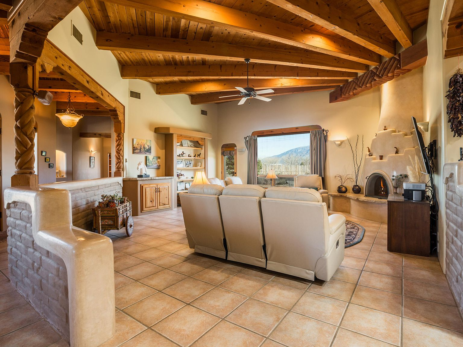 Living room with hand-sculpted plaster fireplace and exposed viga ceiling beams