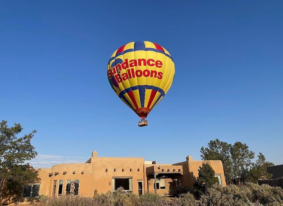 Pueblo-style home with hot air balloon flying overhead during Balloon Fiesta