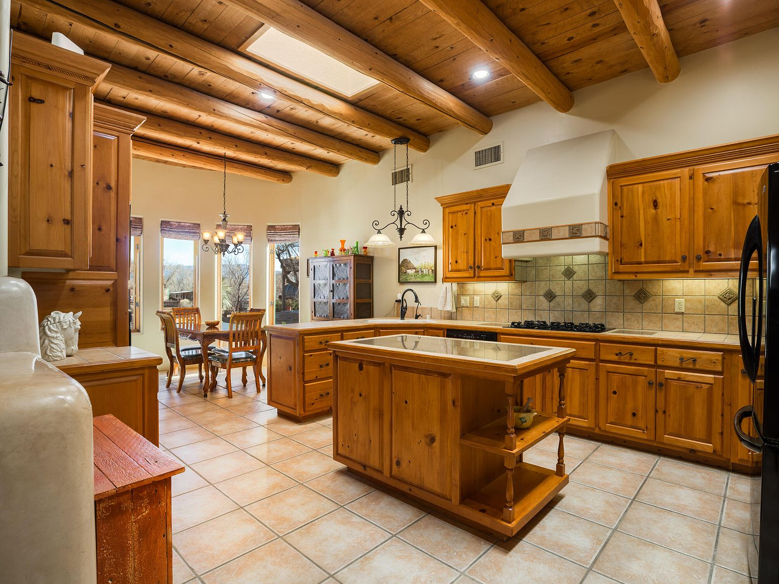 Kitchen with pine viga ceiling, skylight, and knotty pine cabinetry