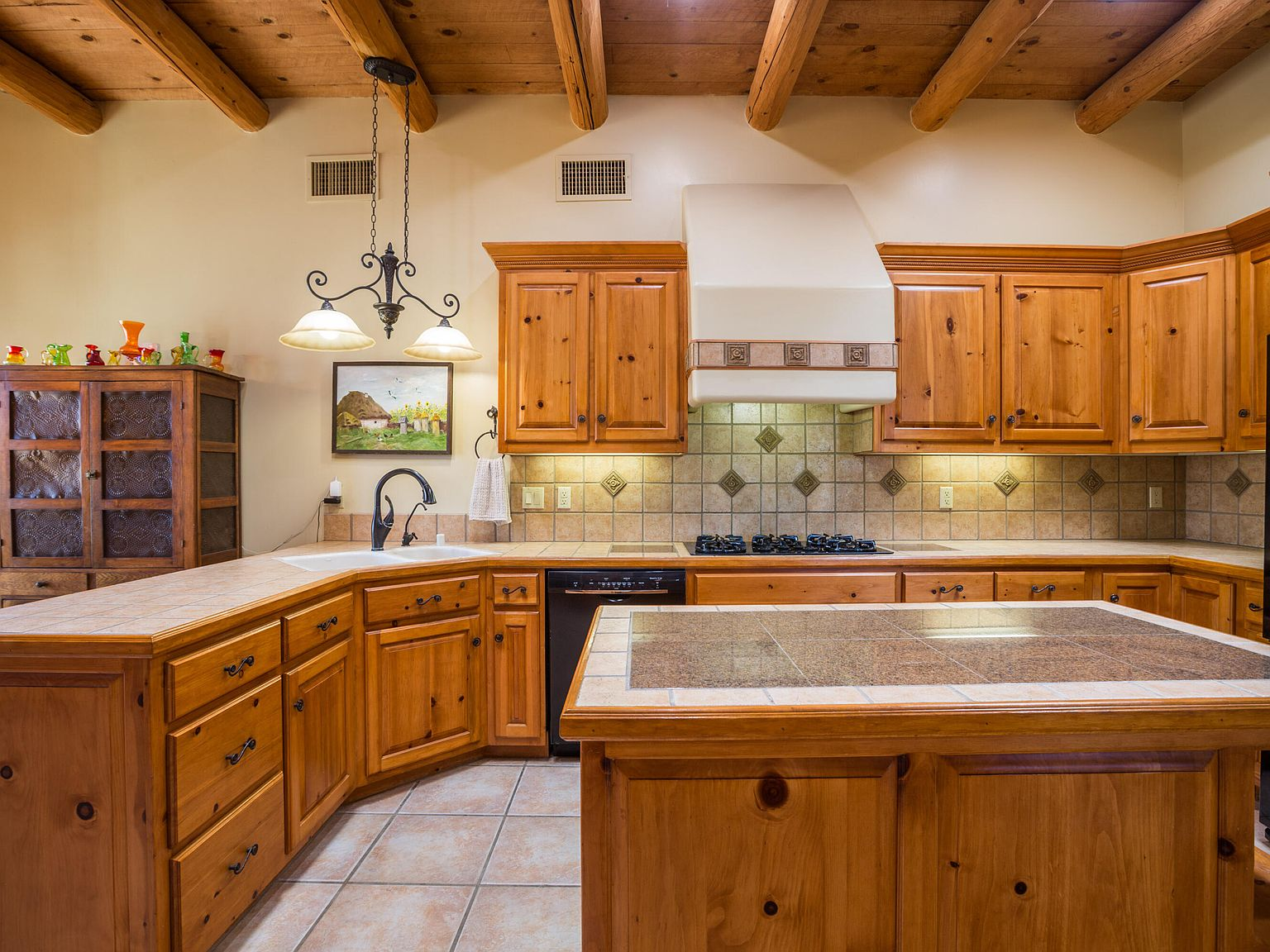 Kitchen with custom wood cabinets, tile countertops, and decorative plaster range hood
