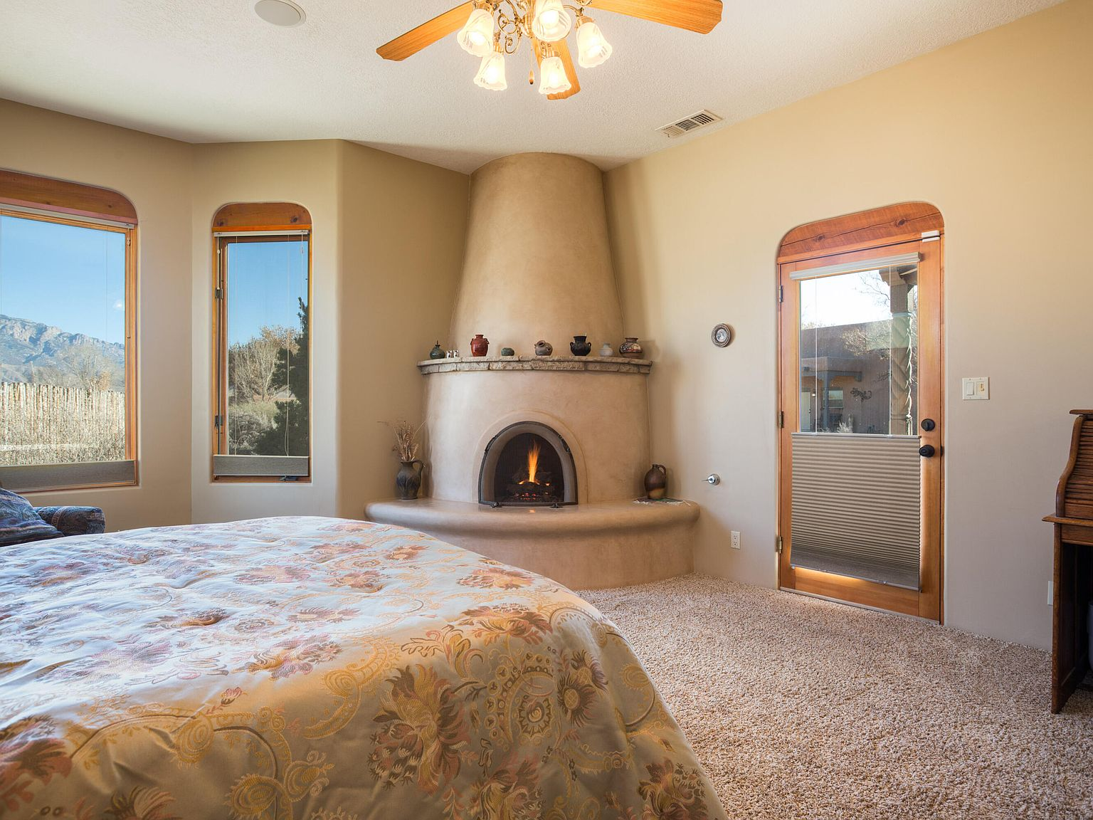 Primary bedroom with kiva fireplace and Sandia Mountain views