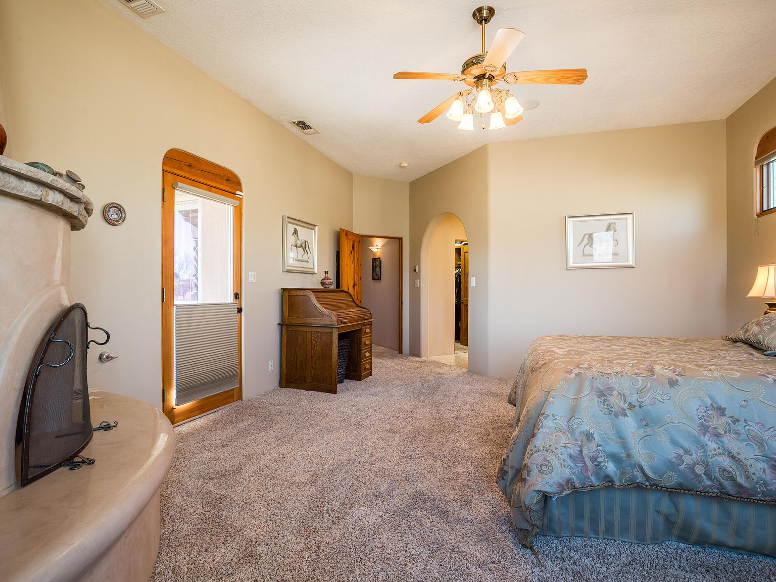 Primary bedroom with hand-sculpted plaster fireplace and arched doors