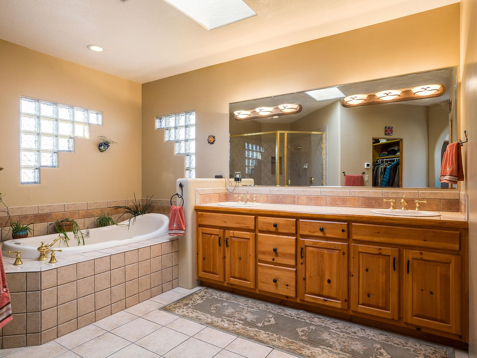 Master bathroom with skylight, tiled tub surround, and pine cabinetry
