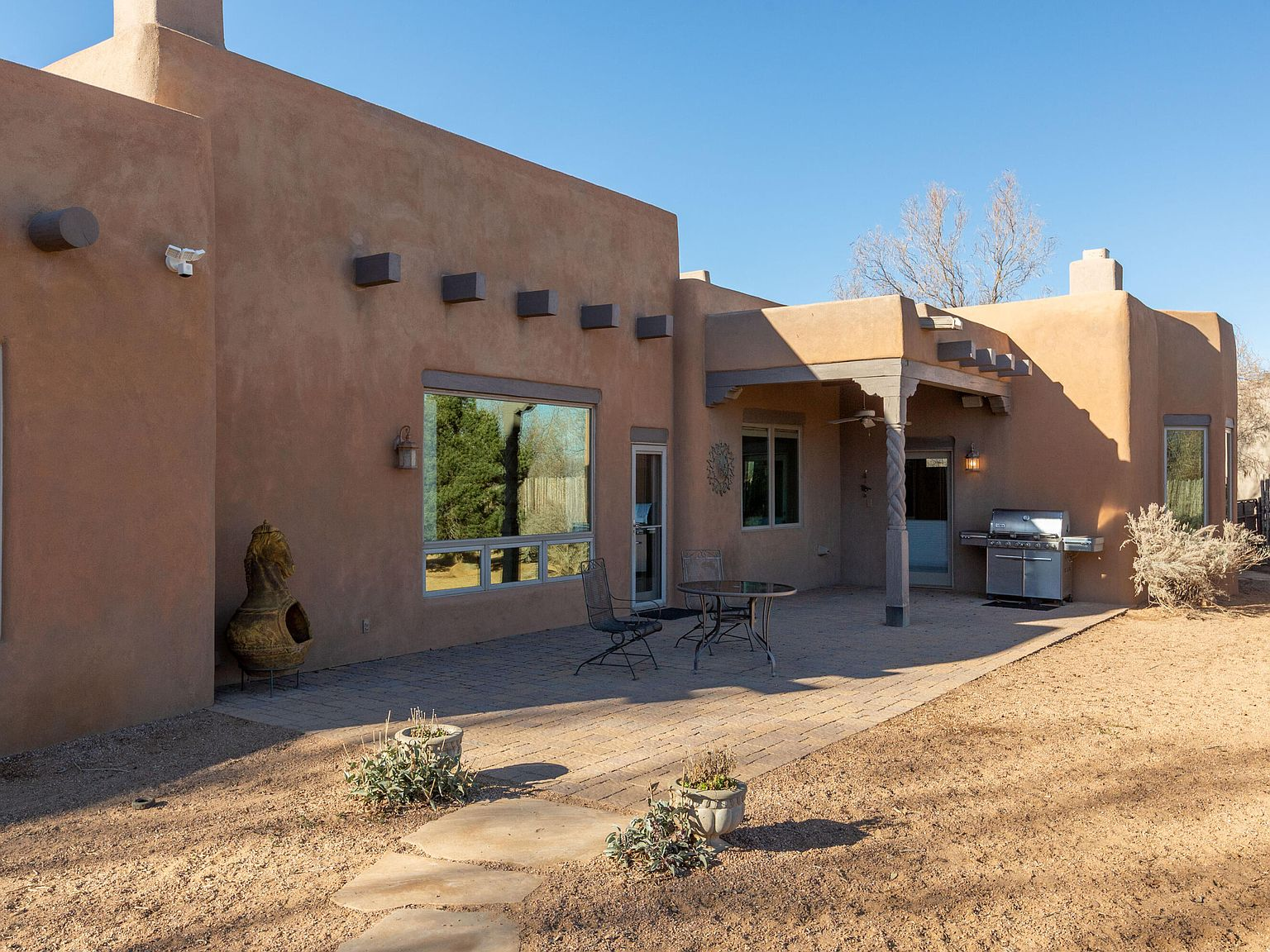 Covered back patio with carved wooden columns and adobe stucco walls